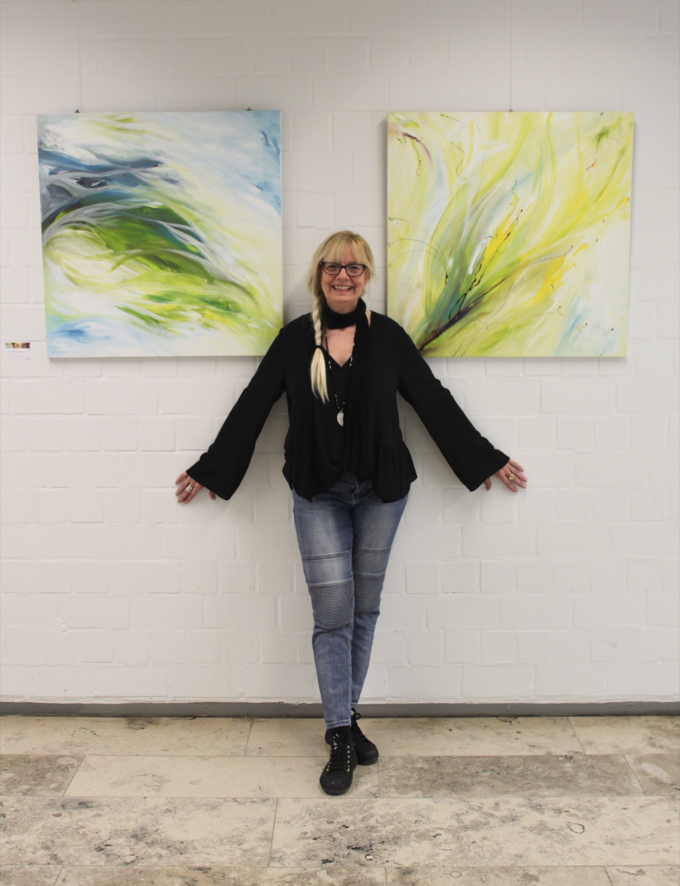 Silvia Grasser zwischen zwei ihrer Gemälde in einer Ausstellung