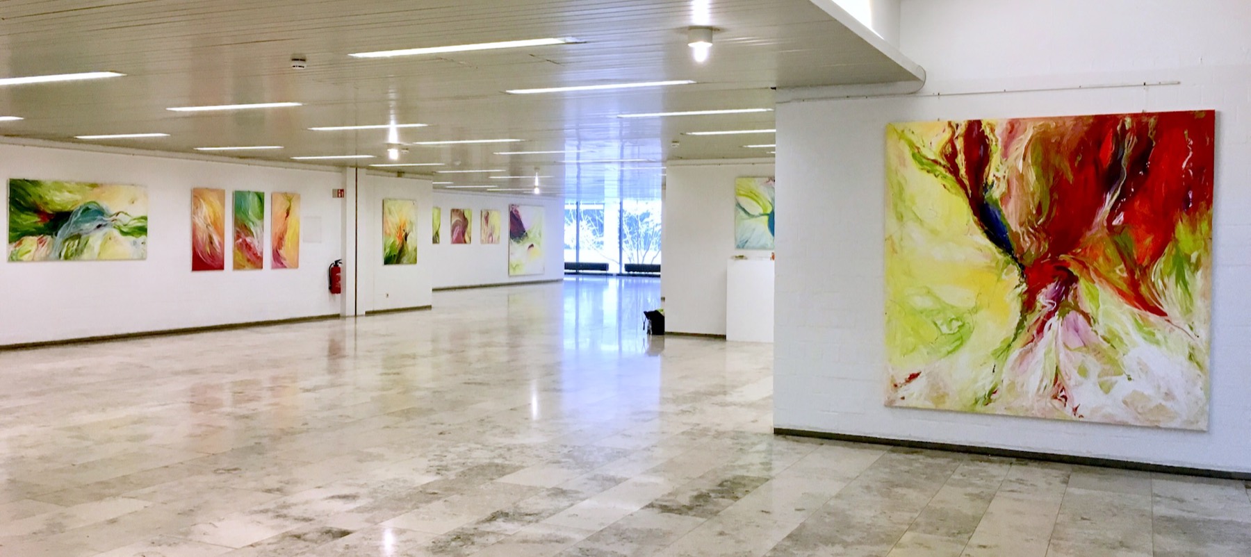 Weite, helle Ausstellungshalle mit vielen großformatigen Acrylbildern von Silvia Grasser